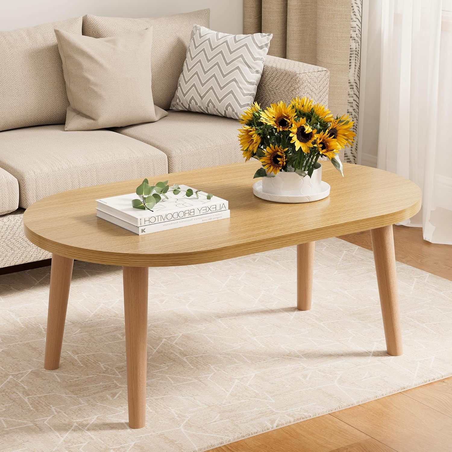 Small oval wooden coffee table with solid wood legs in natural finish